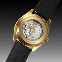 Gold watch with black strap and visible brand name on a gradient background
