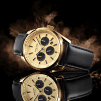 Gold wristwatch with black leather strap on a dark background