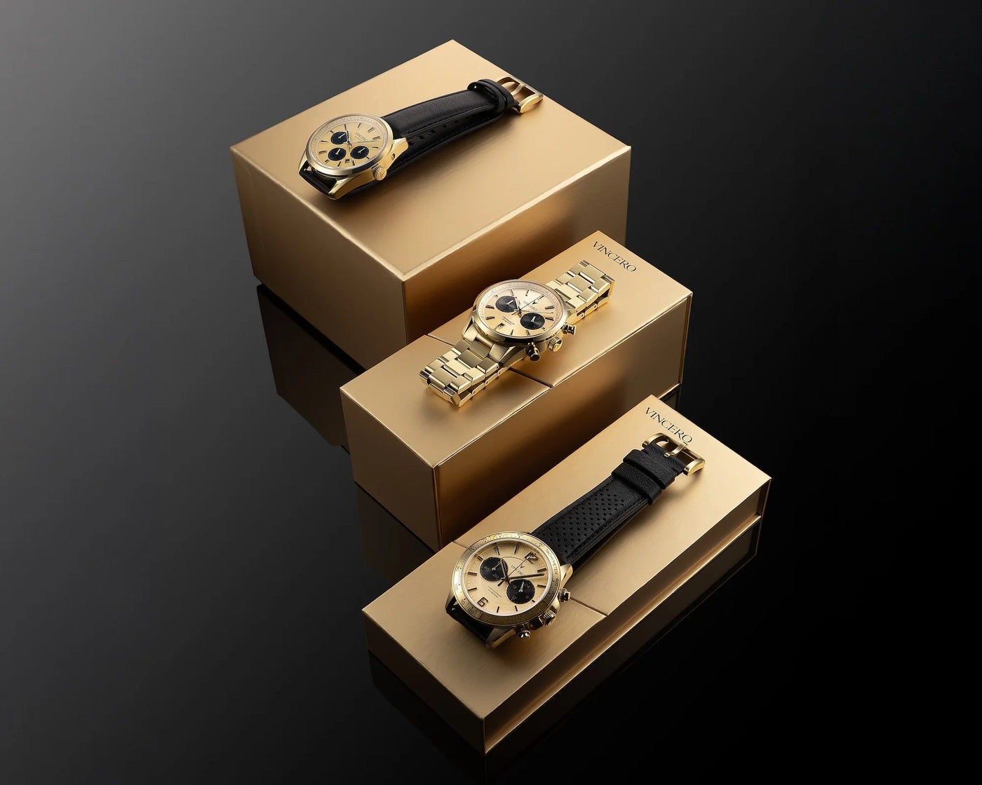 Three gold watches on matching boxes against a dark background