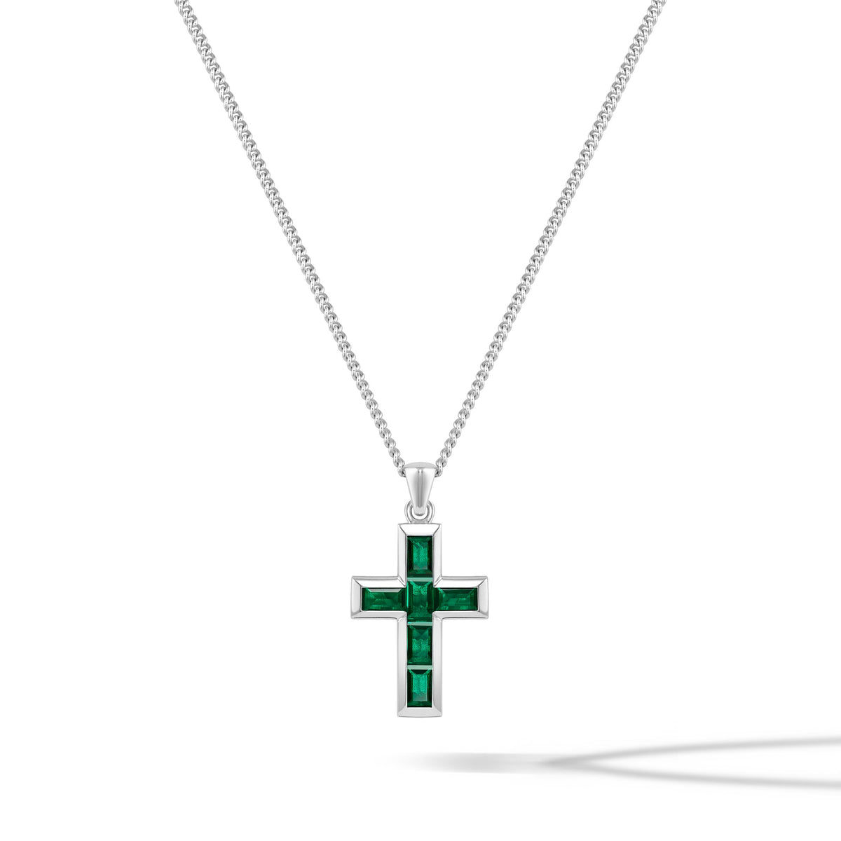 Silver cross pendant with green gemstones on a white background