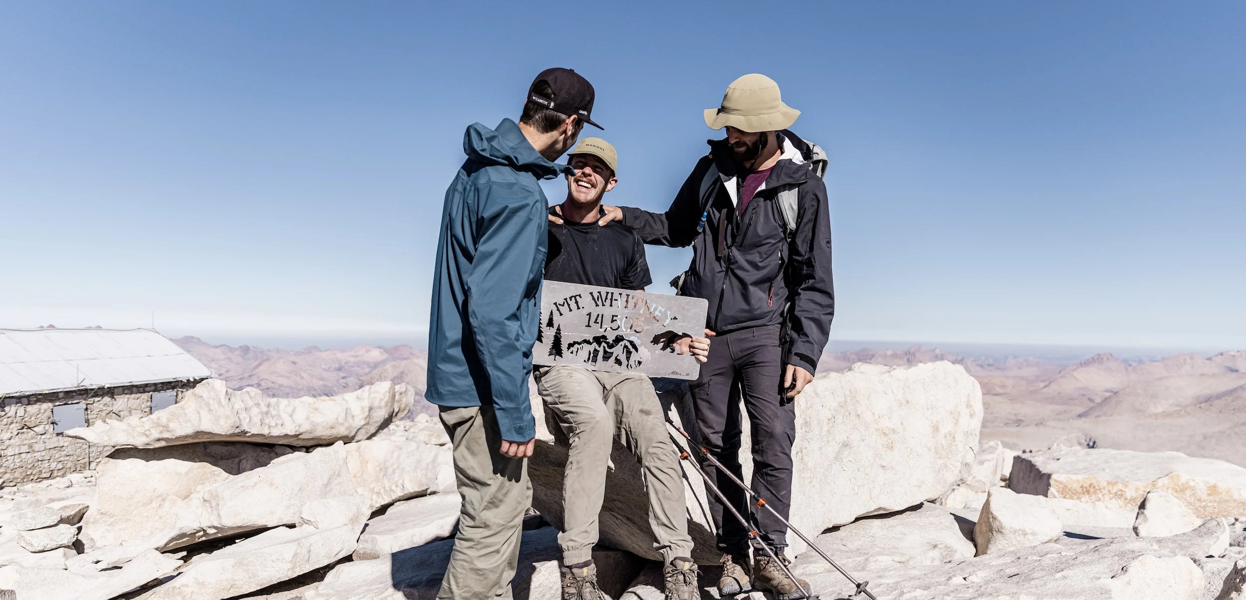 Three men standing together on the summit of Mt Whitney
