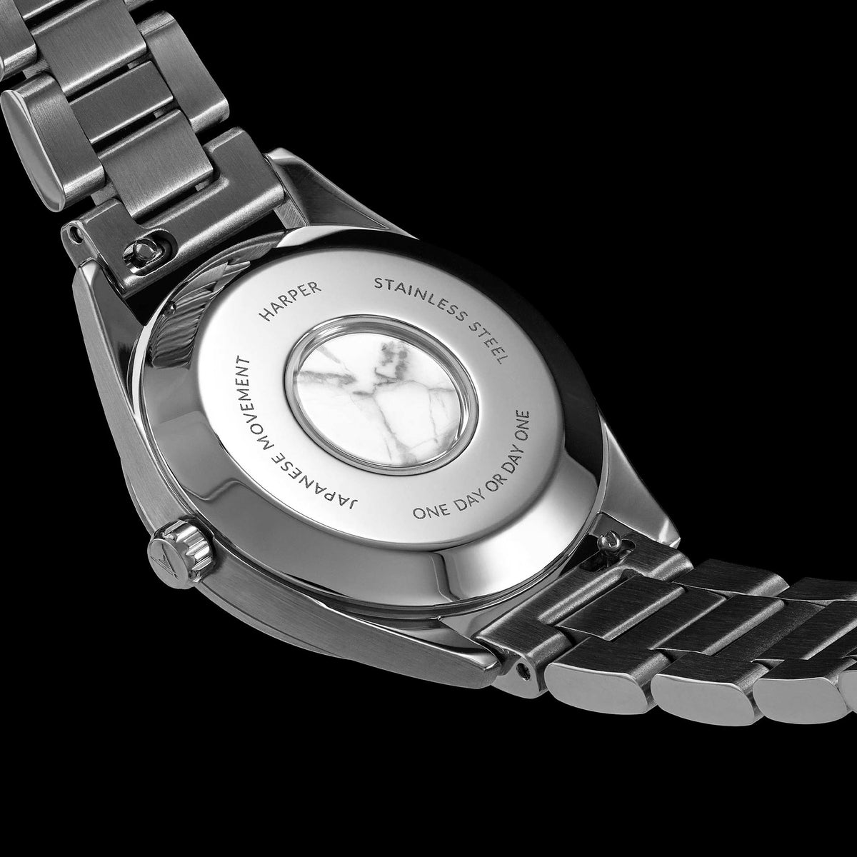 Close-up of a silver watch with visible brand name on a black background