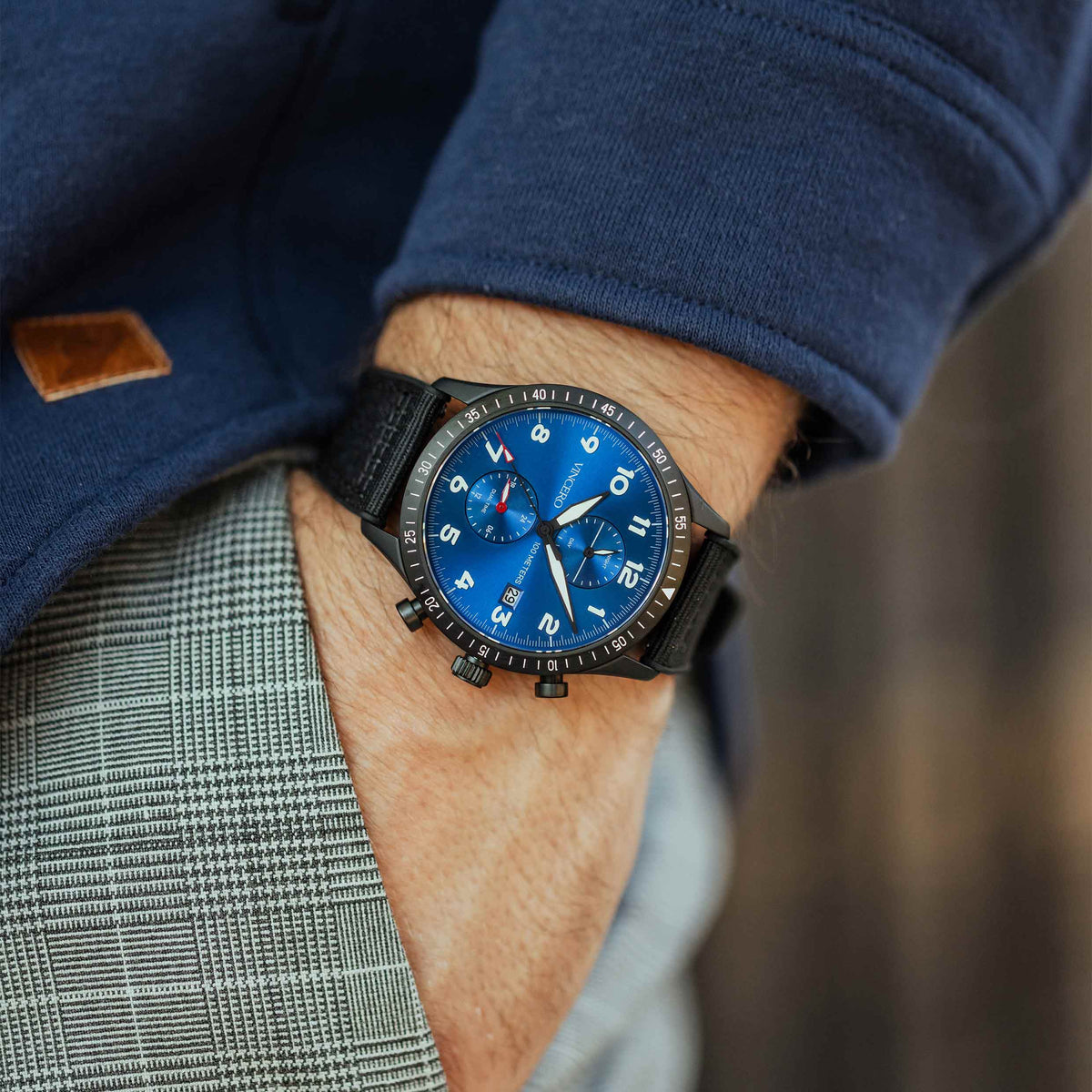 Close-up of a person wearing a blue watch with a dark strap.