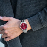 Person wearing a watch with a red face and silver case.