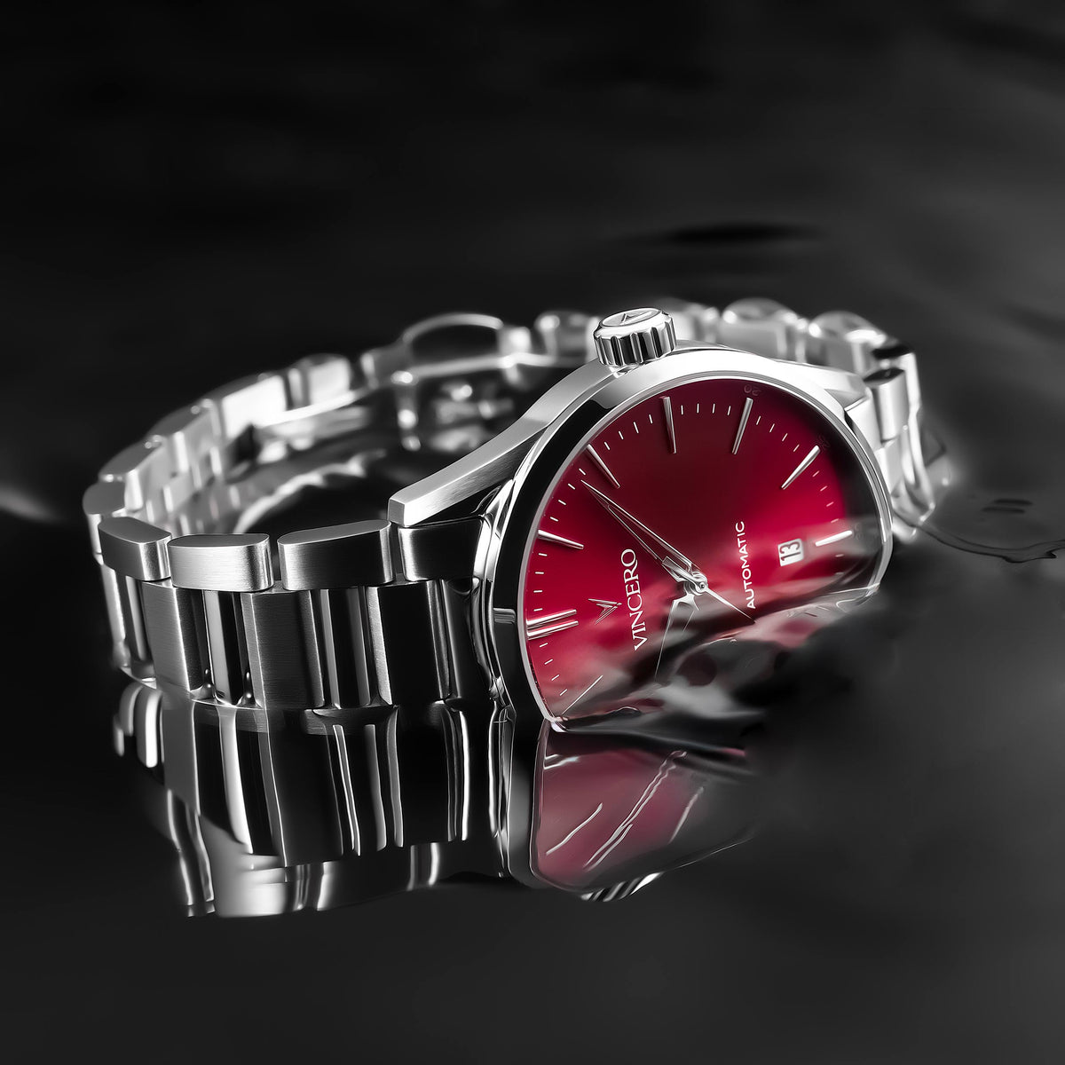 Silver watch with a red face on a reflective black surface