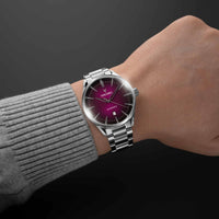 Silver watch with a purple face on a wrist, against a dark background