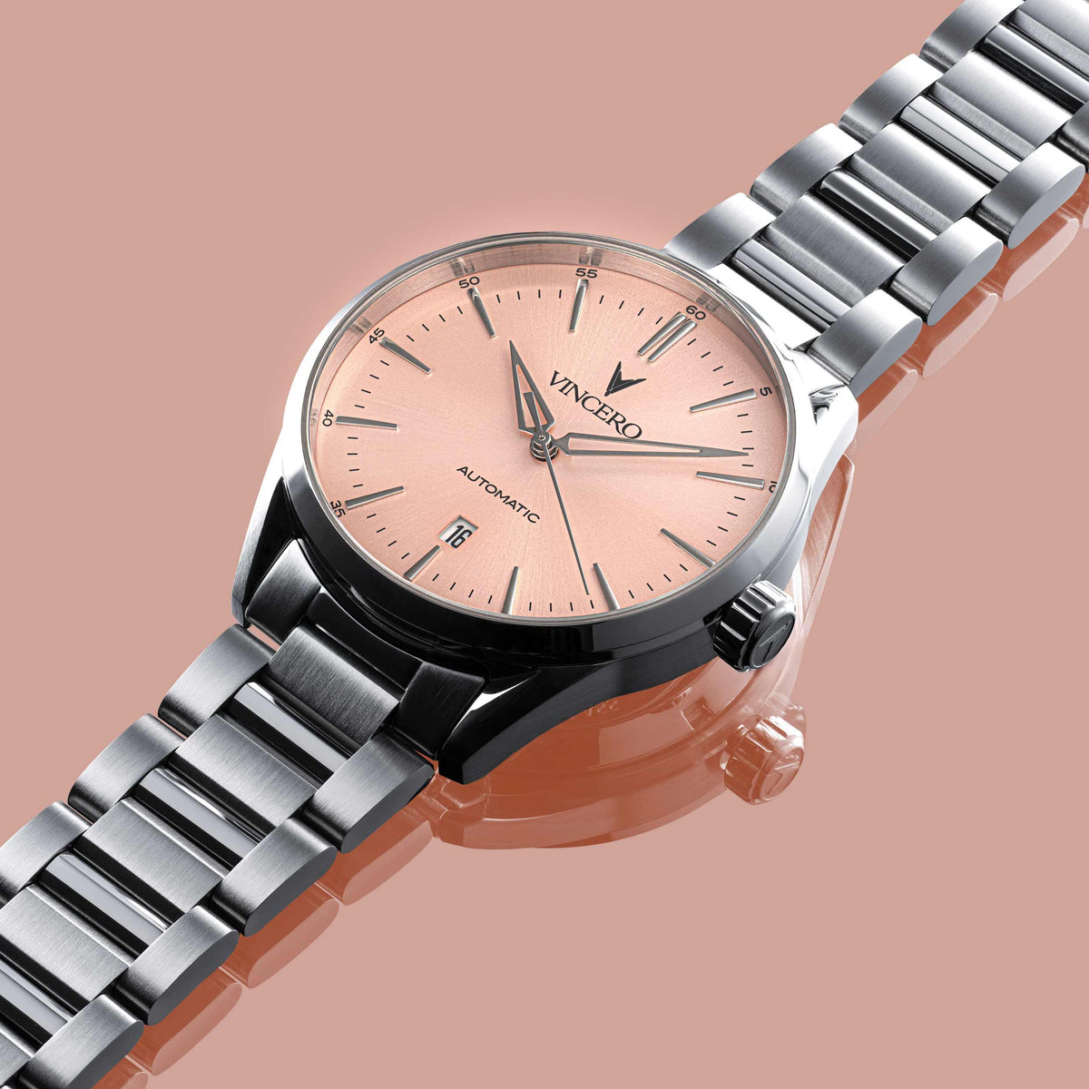 Silver watch with a pink face on a peach background