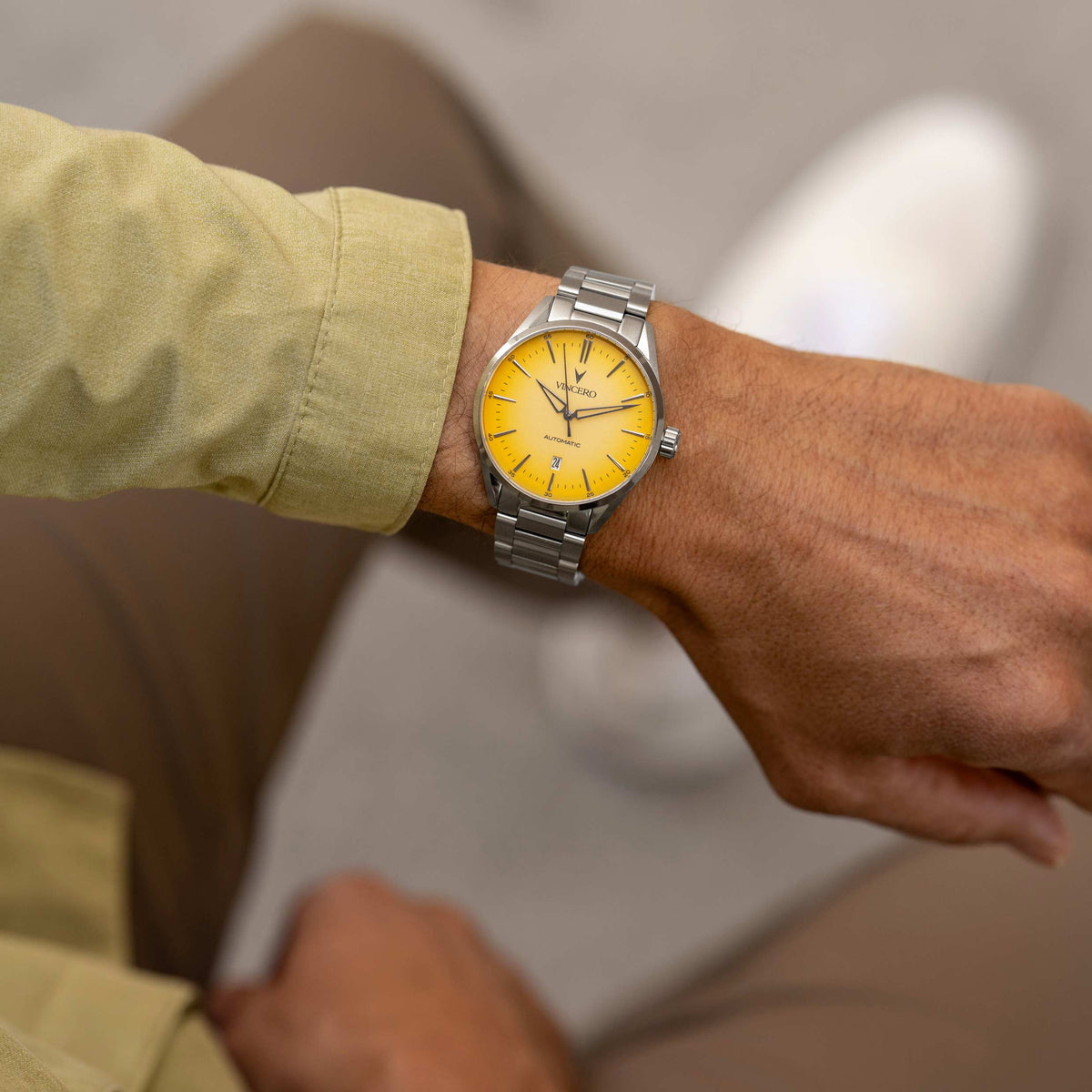 Man looking at his wrist, wearing a Solar Flare Edition watch, featuring a yellow face, stainless steel casing, and steel band.