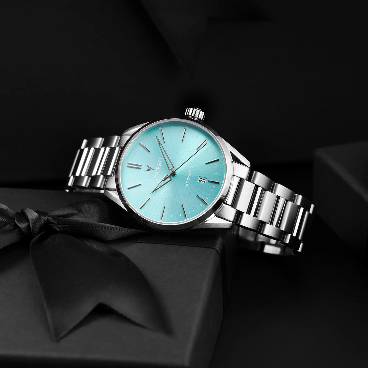 Silver watch with a turquoise face on a black background