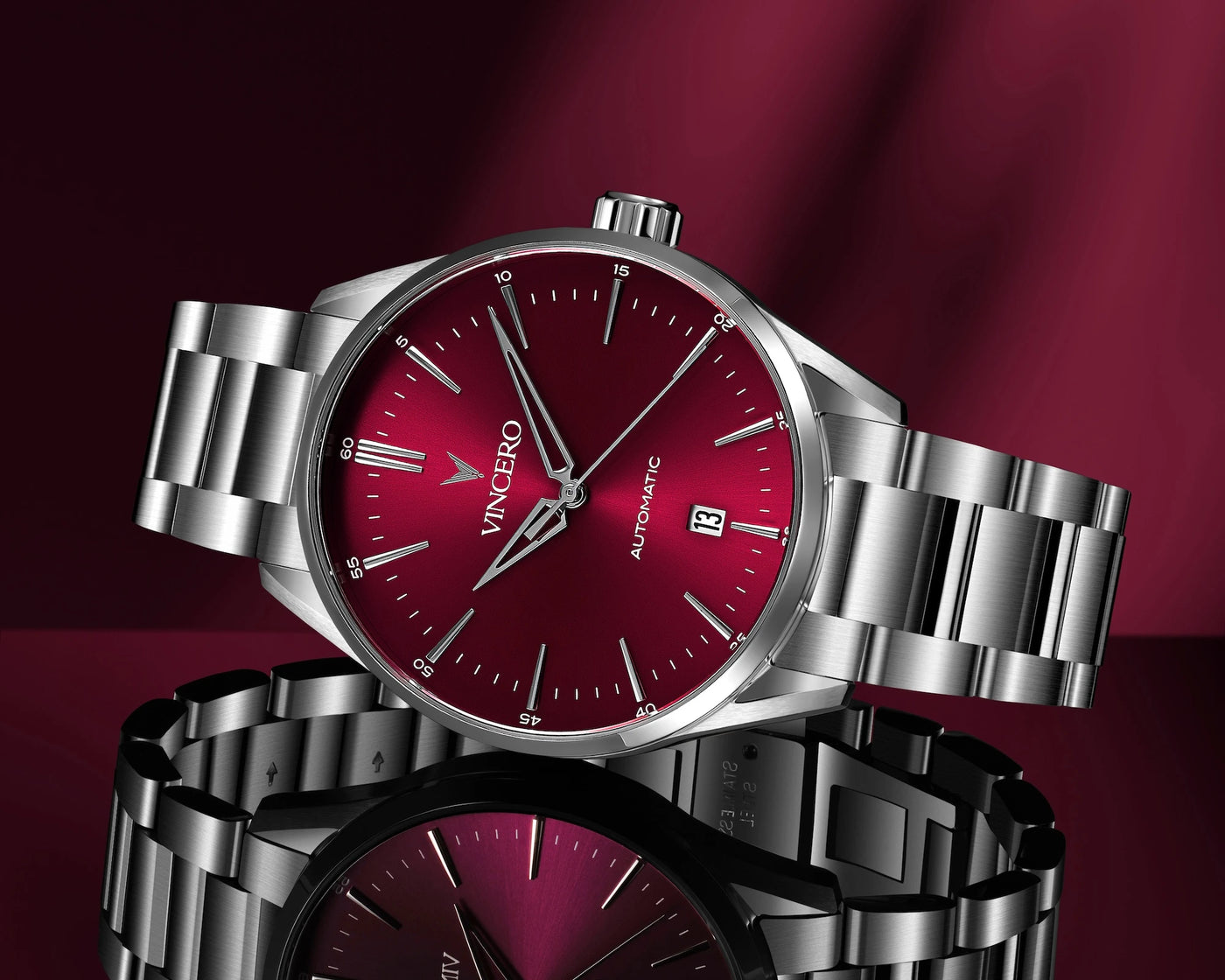 Silver watch with a red face on a dark red background, featuring the brand 'Vincero'.