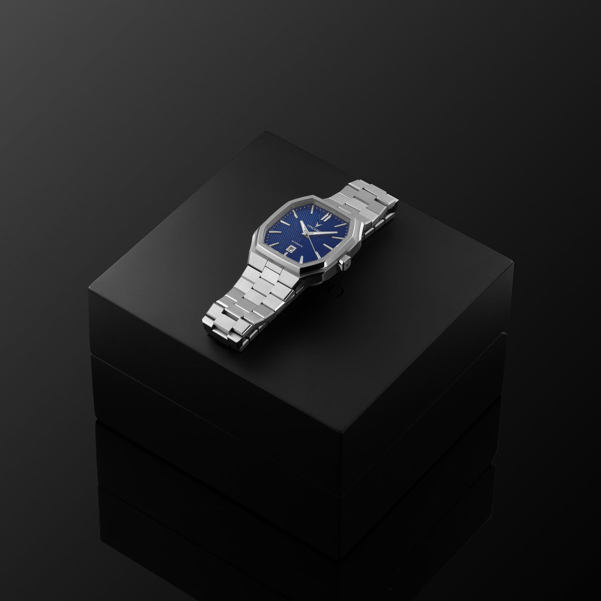 Silver watch with a blue face on a black reflective surface