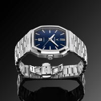 Silver watch with blue dial on a reflective black surface