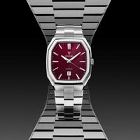 Watch with red face and silver metal strap on a black background