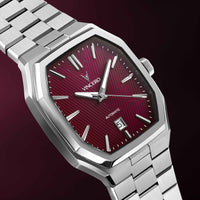 Silver wristwatch with a maroon face on a dark background
