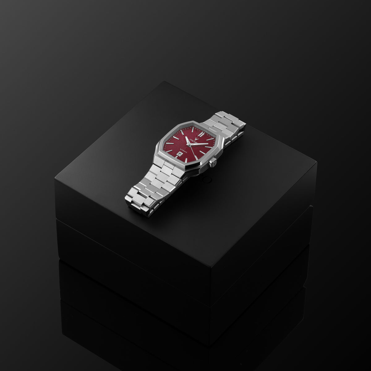 Silver watch with a red face on a black reflective surface