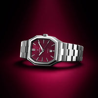 Luxury watch with red face and silver metal strap on a dark red background