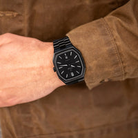 Black watch on a wrist with a brown jacket