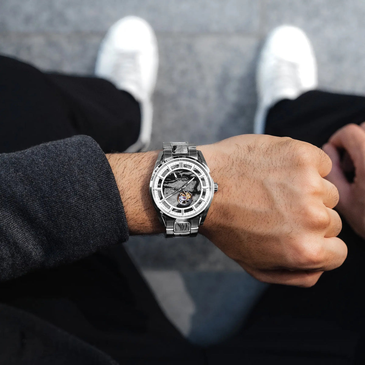 Close-up of a wrist wearing a silver watch with a blurred background