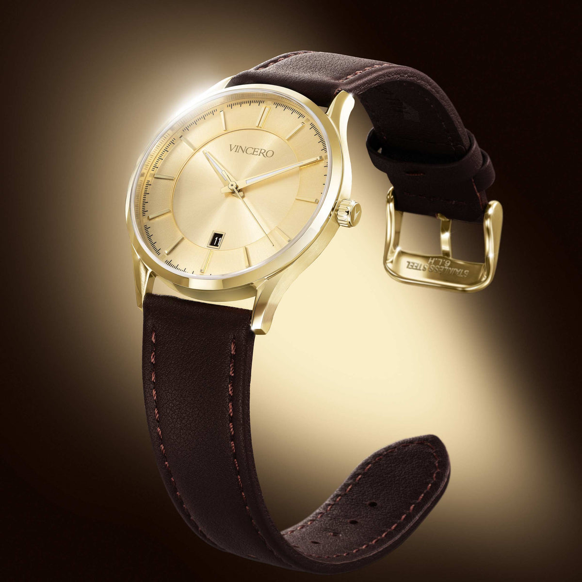 A luxury wristwatch by VINCERO, featuring a gold-tone round case, a champagne-gold dial with a date window, and a dark brown leather strap with visible stitching and a gold buckle, set against a dark brown background with a warm spotlight glow.