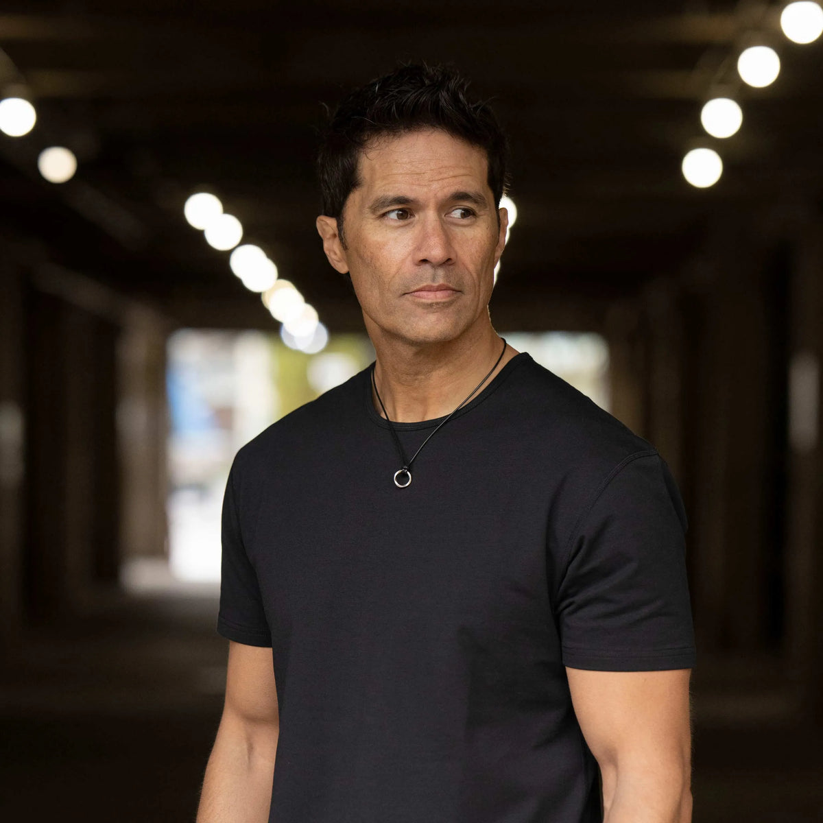 A sterling silver amulet pendant with a silver curb chain necklace and a black waxed cord.