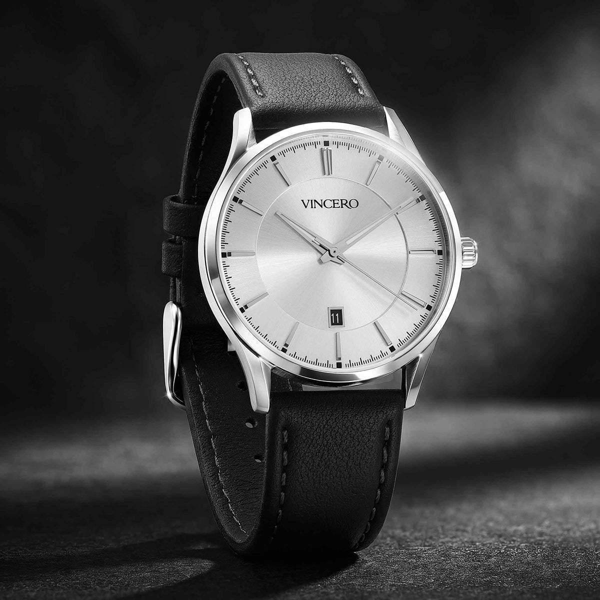 A VINCERO men's analog watch with a silver-toned stainless steel case, a silver dial, and a black leather strap, shown on a dark textured background.