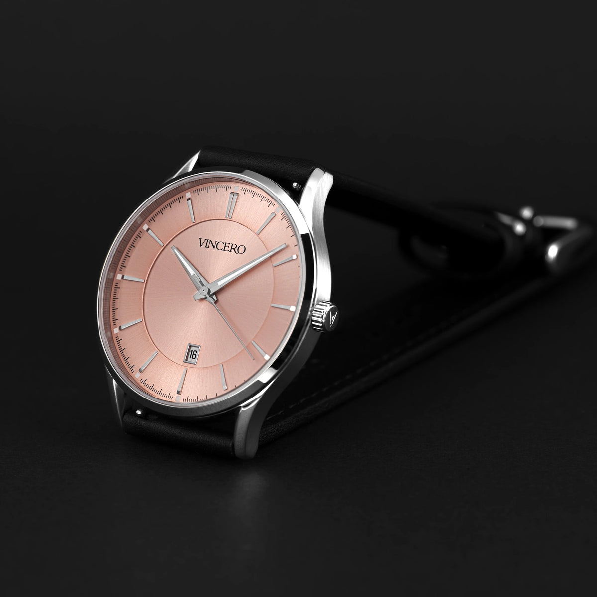 Wristwatch with pink dial and black strap on a dark background