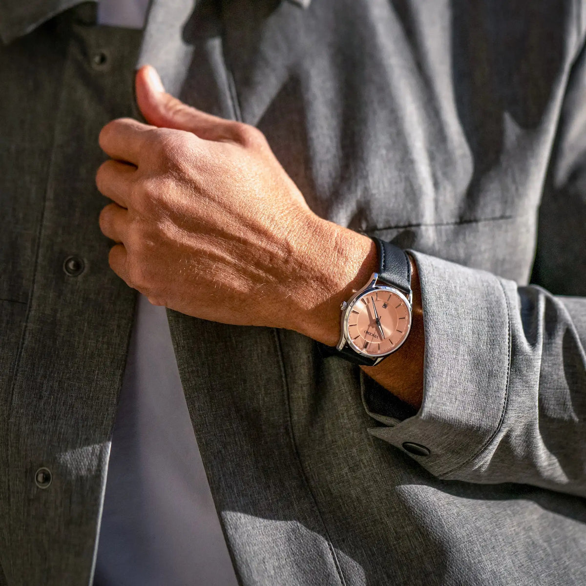 Person wearing a watch with a gray shirt and jacket