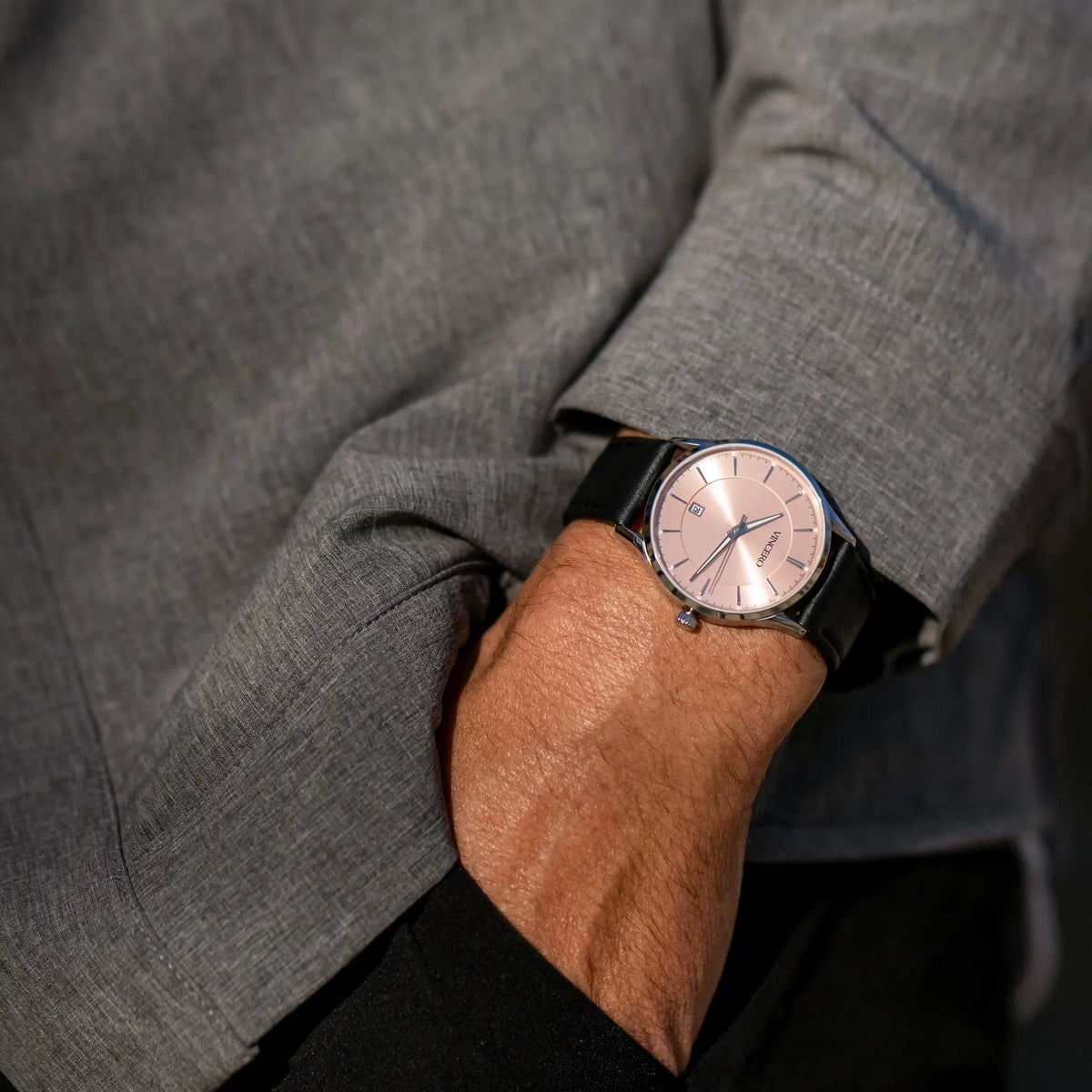Person wearing a gray suit with a watch on their wrist