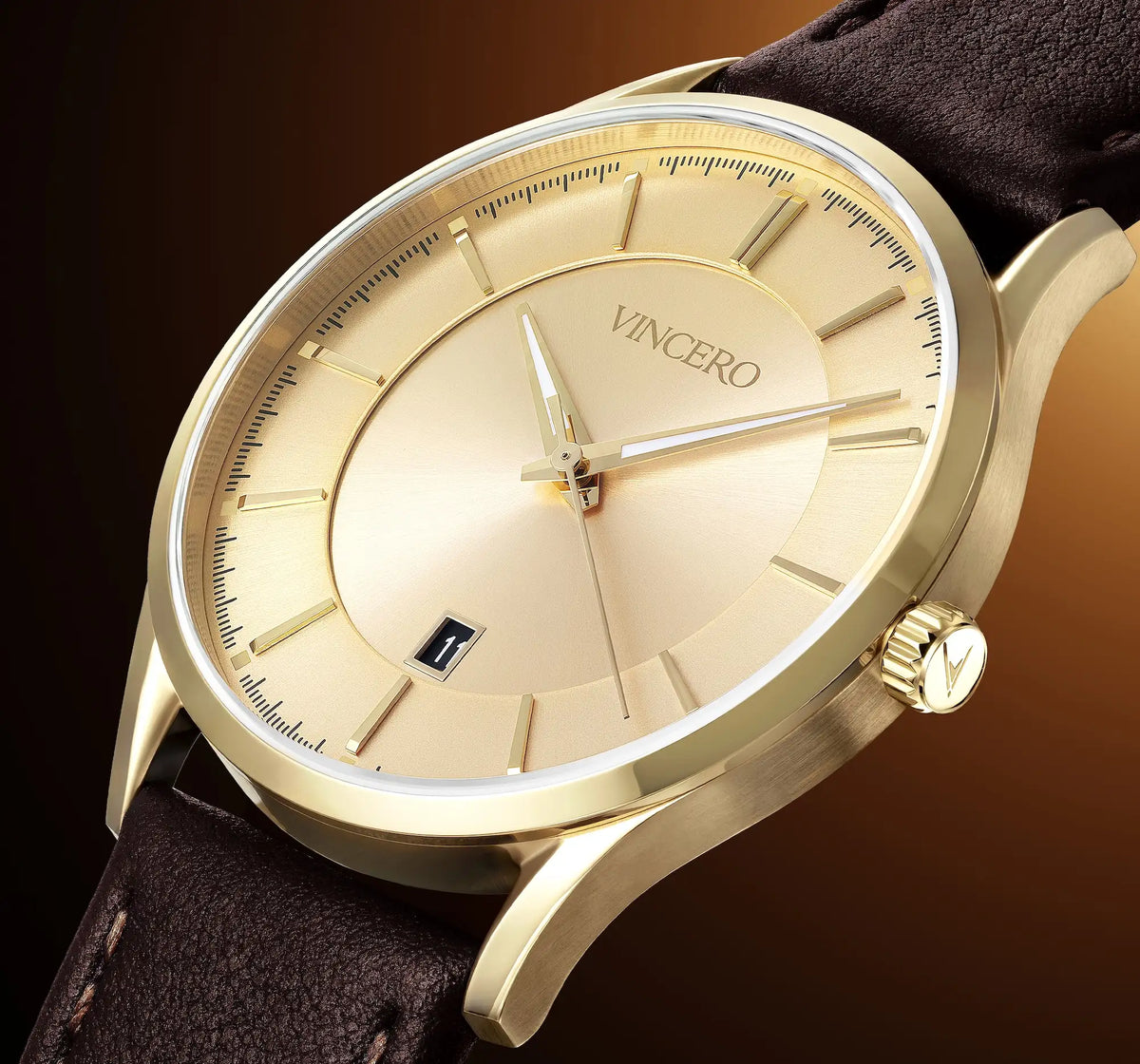 A close-up shot of a VINCERO men's watch featuring a gold-tone stainless steel case, a champagne-gold dial with slim stick indices, a date window at 3 o'clock, and a dark brown leather strap.