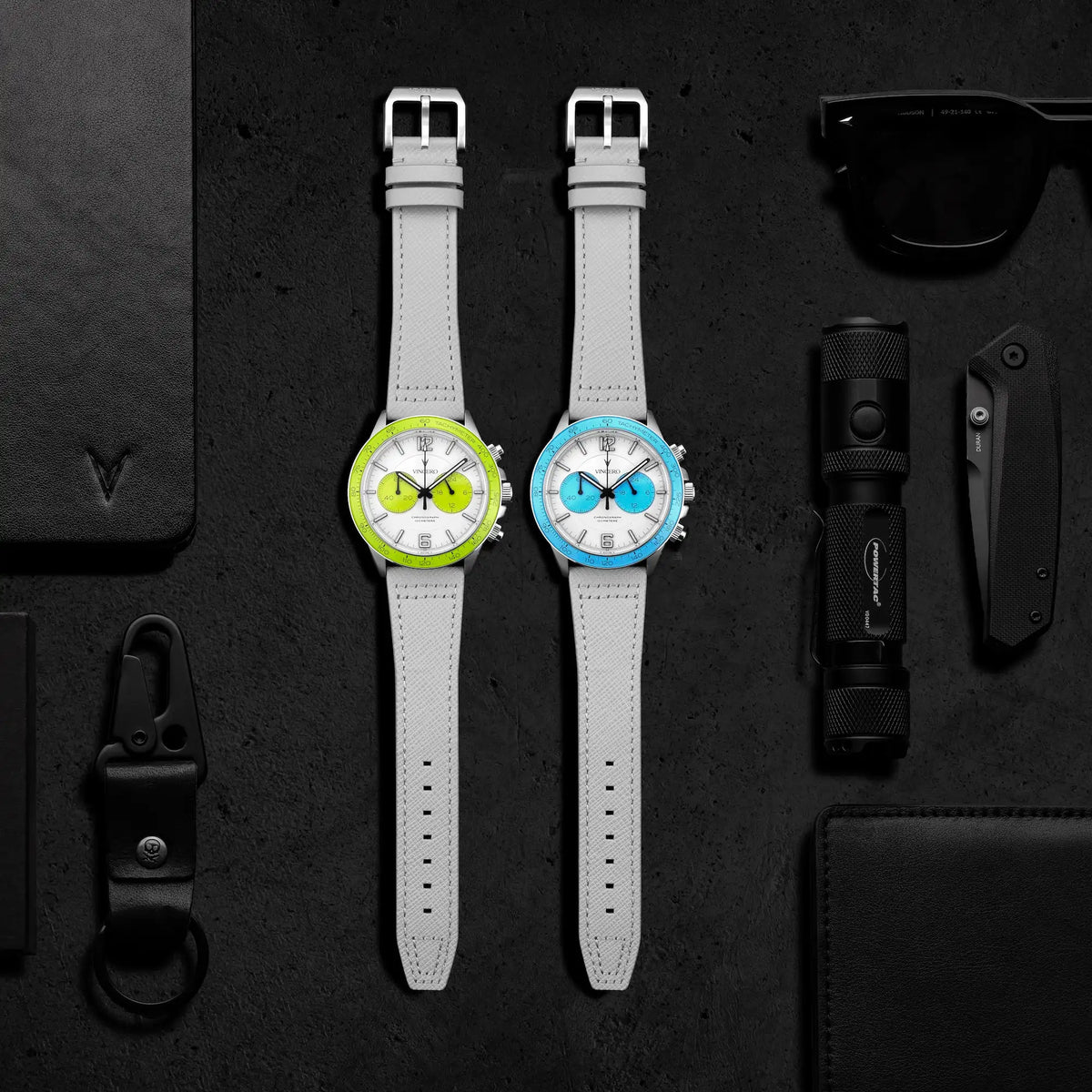 Two gray watches with colorful faces on a dark textured surface.