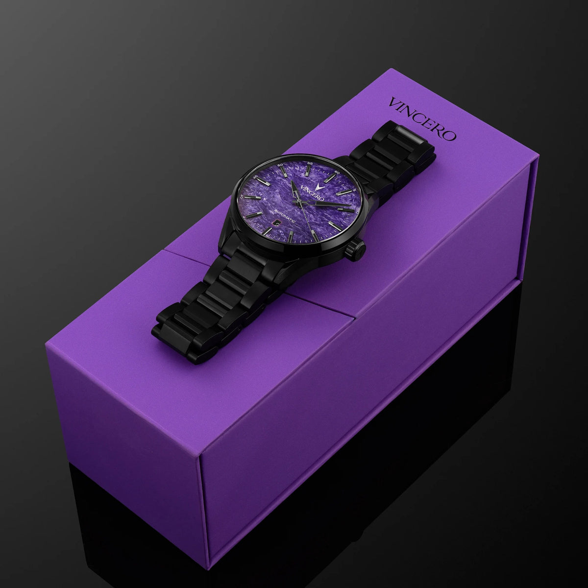 A black analog watch with a textured purple dial rests diagonally on top of a purple rectangular box. The brand name 'VINCERO' is printed in gold on the top right corner of the box.