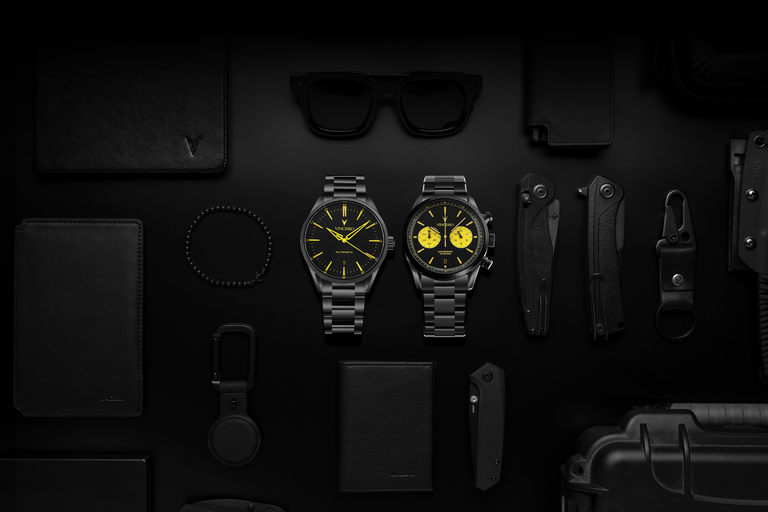 Two black watches with yellow accents on a dark background with various items.