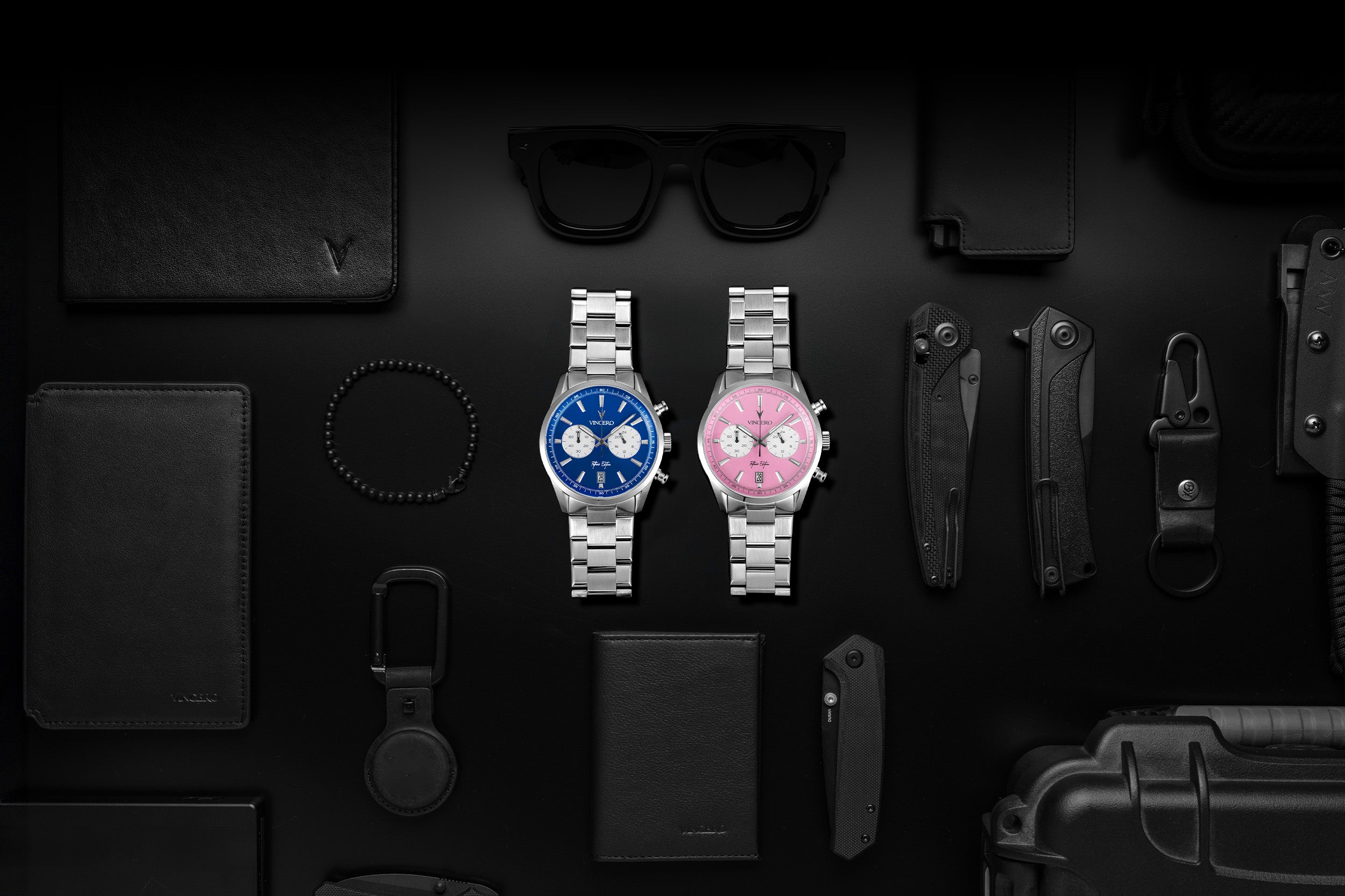 Father’s Edition watches placed on a black mat with EDC items. One watch features a pink face, stainless steel casing, and steel band; the other features a blue face, stainless steel casing, and steel band.