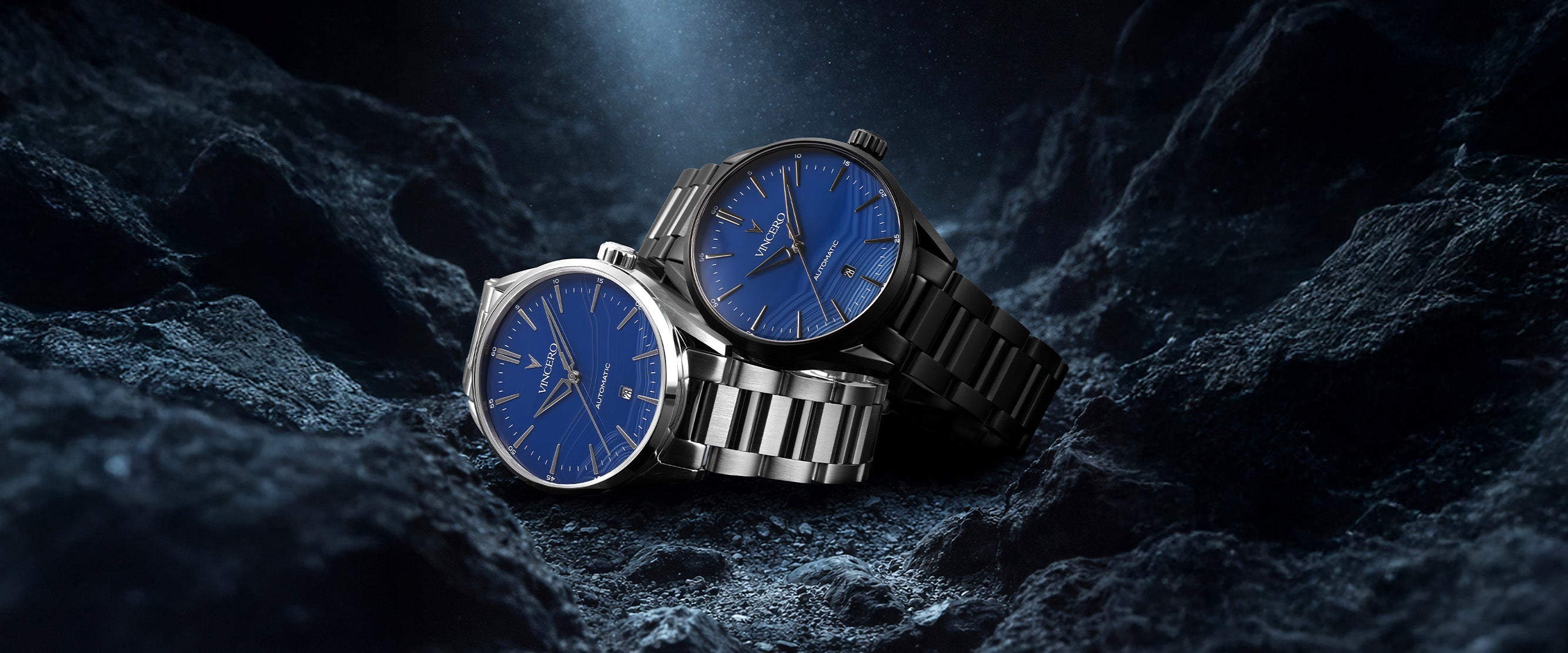 Two watches with blue faces and silver and black cases on a dark textured background