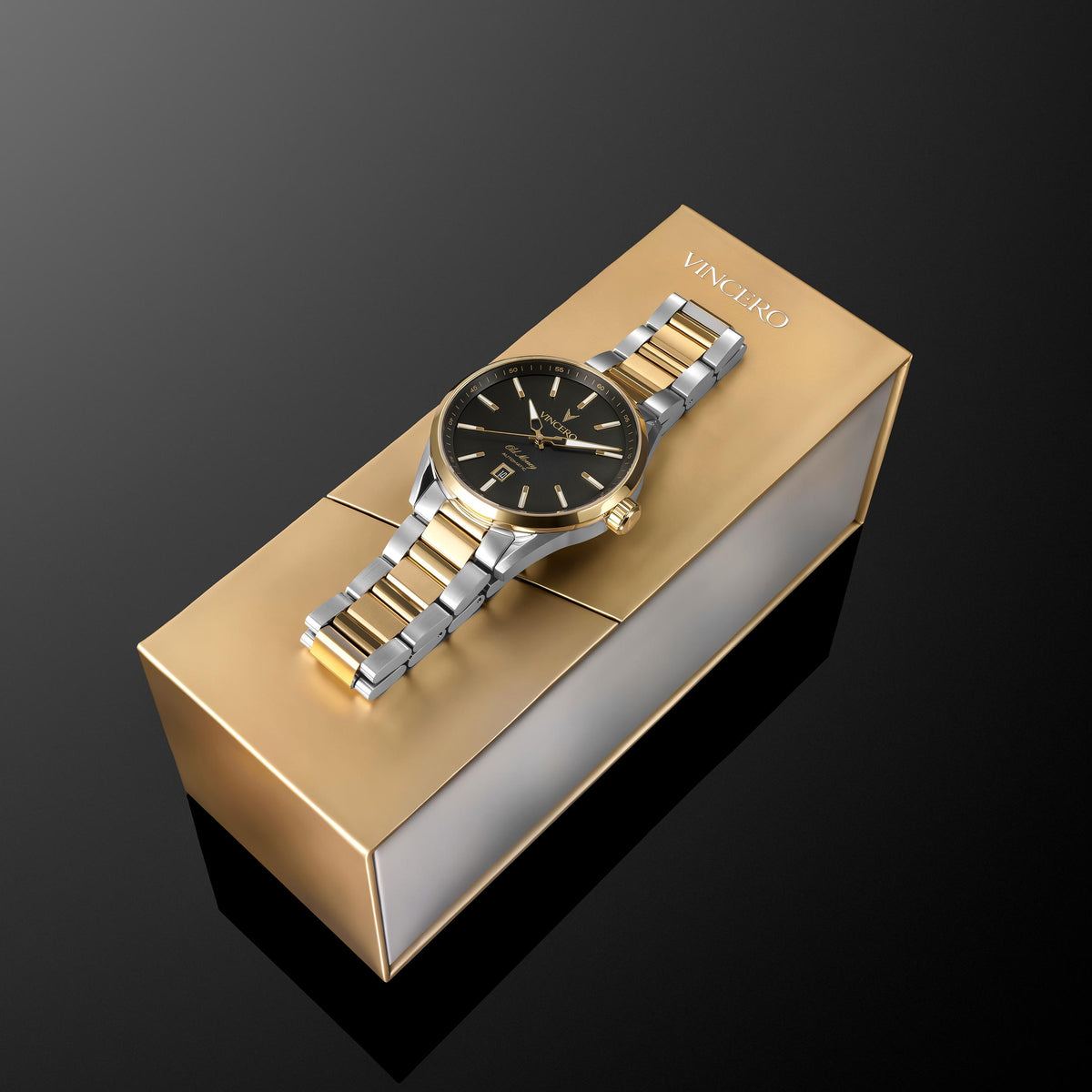 A luxury wristwatch with a two-tone gold and silver metal bracelet and a black dial, presented on top of its gold-colored rectangular box. The brand name 'VINCIATO' is printed on the top of the box.