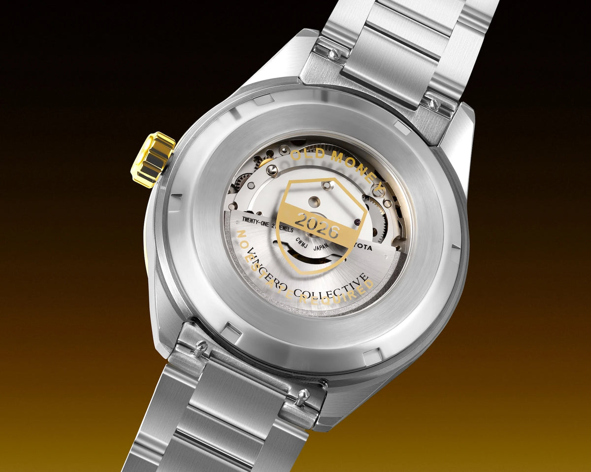 Close-up of a stainless steel wristwatch showing the transparent back case and automatic movement, with a gold-tone crown and a yellow-gold central accent on the dial.