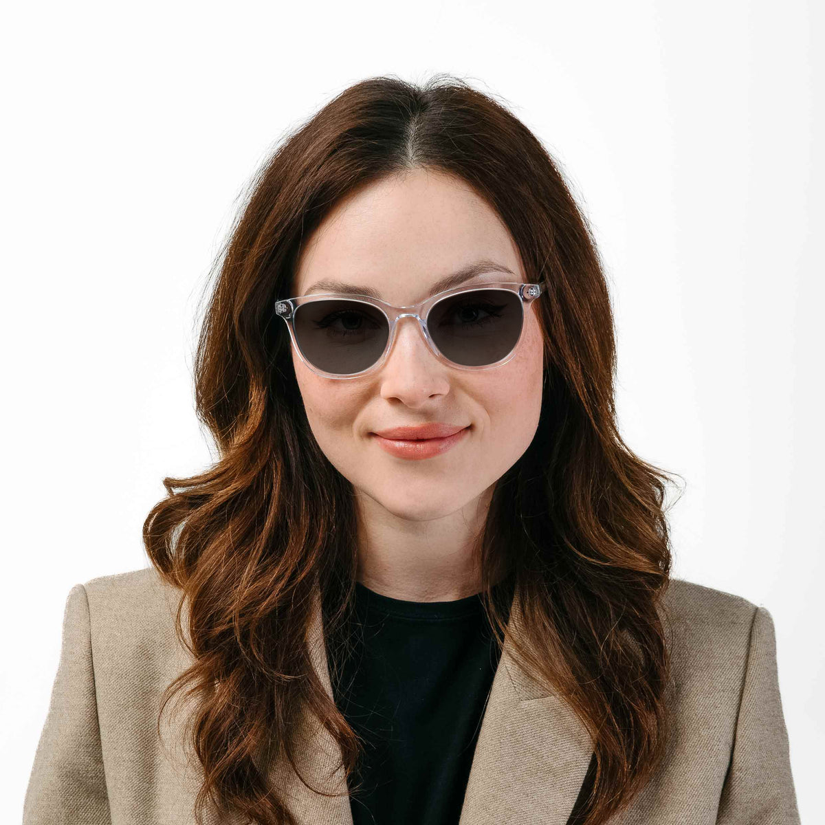 Woman wearing sunglasses and a beige blazer on a white background