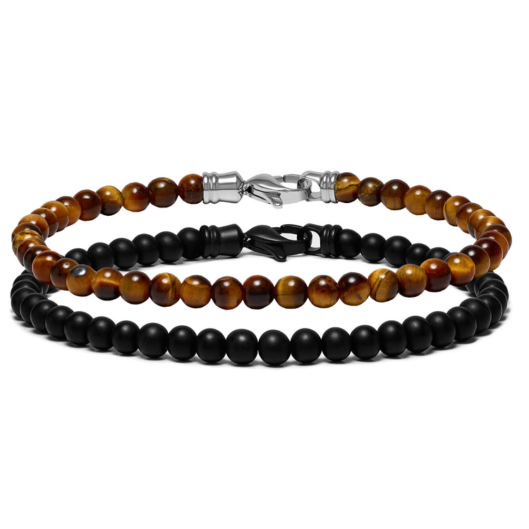 Two beaded bracelets, one with black onyx beads and another with tiger eye beads, laid one over the other.
