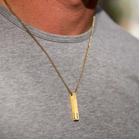 Gold necklace with a vertical pendant on a gray shirt