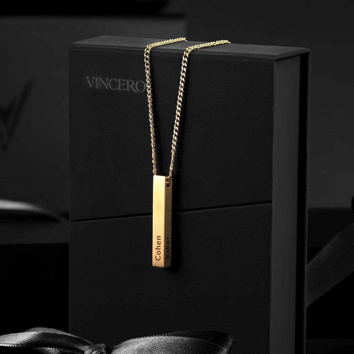 Gold necklace with a pendant on a black box, featuring the brand 'Vincero'.