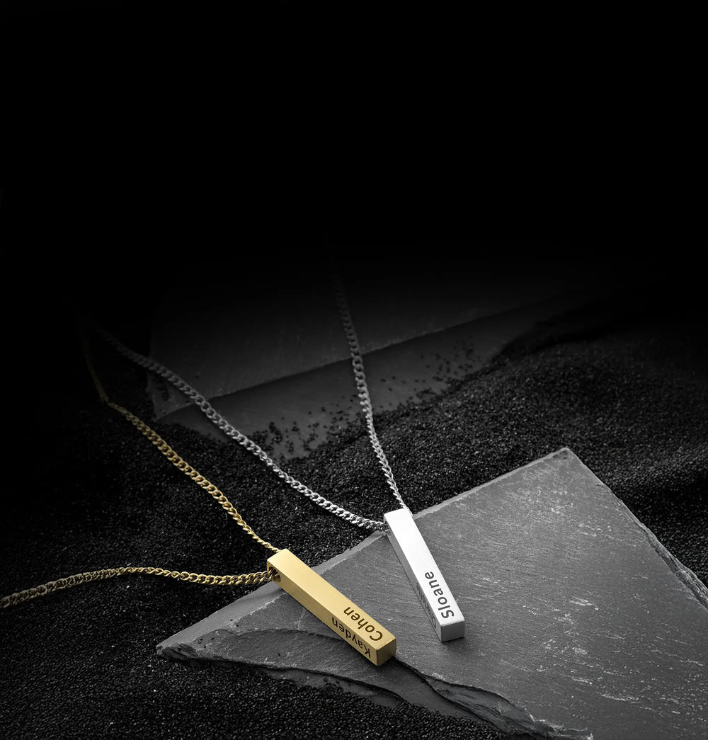 Two necklaces with engraved names on a dark surface