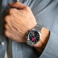 Silver watch on a person's wrist with a checkered shirt background
