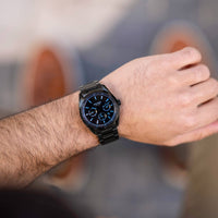 Person wearing a black smartwatch with a blurred background