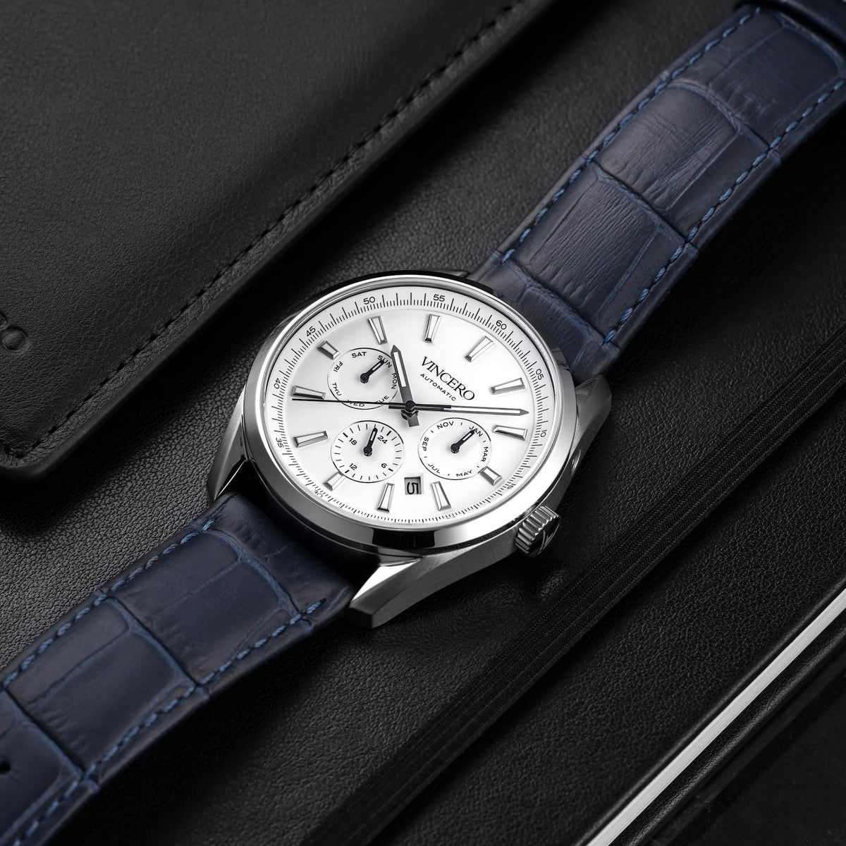 Luxury watch with blue strap on a dark textured surface