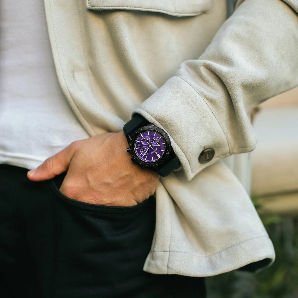 Person wearing a beige coat with a watch on their wrist, blurred background