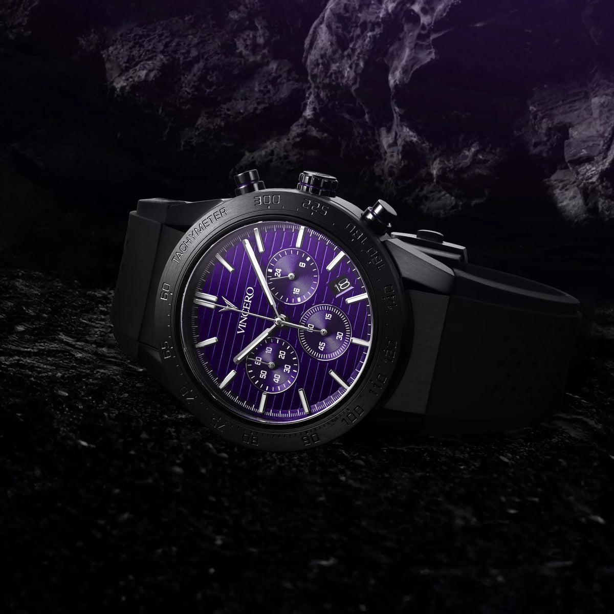 Black watch with purple face on a dark, rocky surface