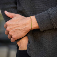 Person wearing a gold bracelet with a blurred background