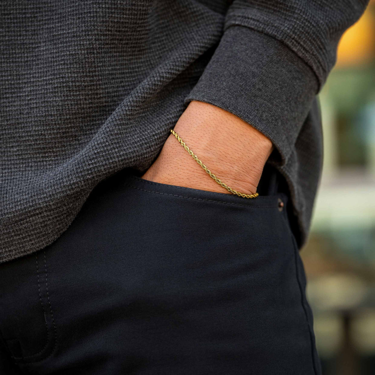 Person wearing a gold bracelet with a blurred background