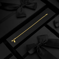 Gold bracelet on a black gift box with ribbons