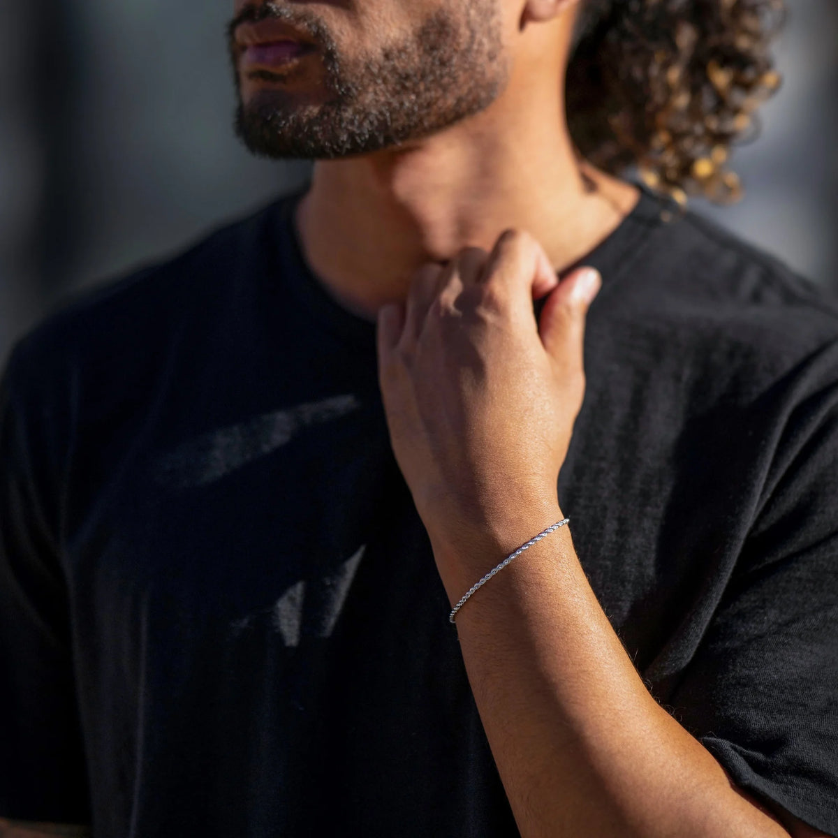 Person wearing a black shirt with another hand touching their neck